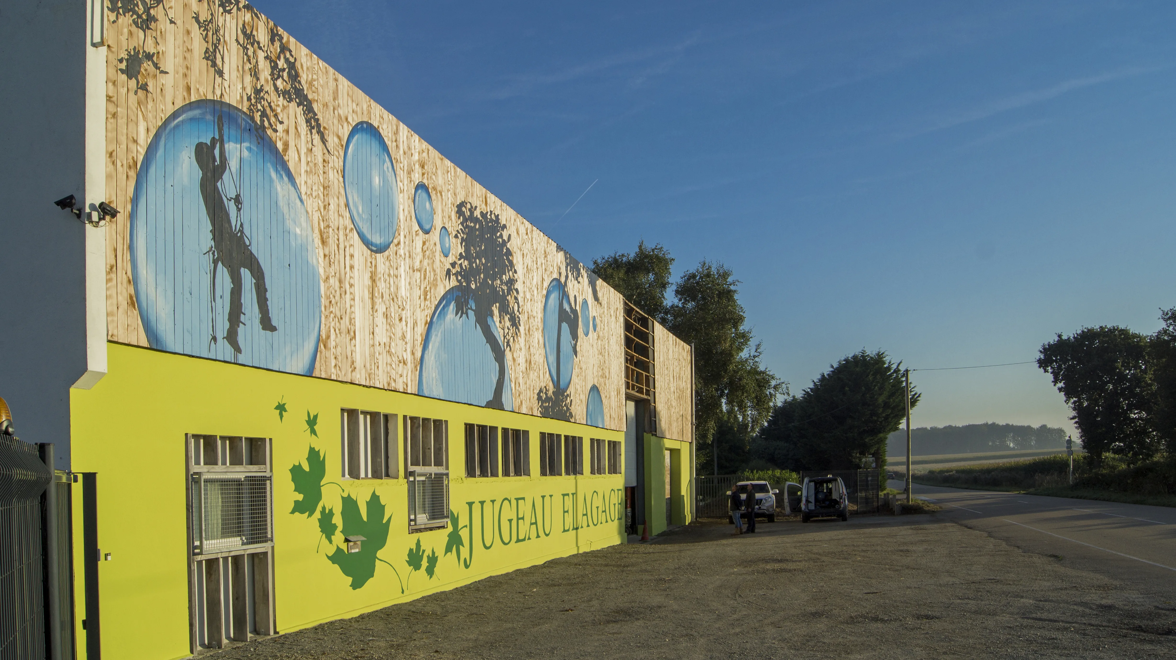 Vue de 3/4: bâtiment jugeau élagage décoré de bulles, d'arbres noirs et d'un lettrage peint